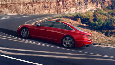 Red Audi S6 Saloon side driving up mountain road