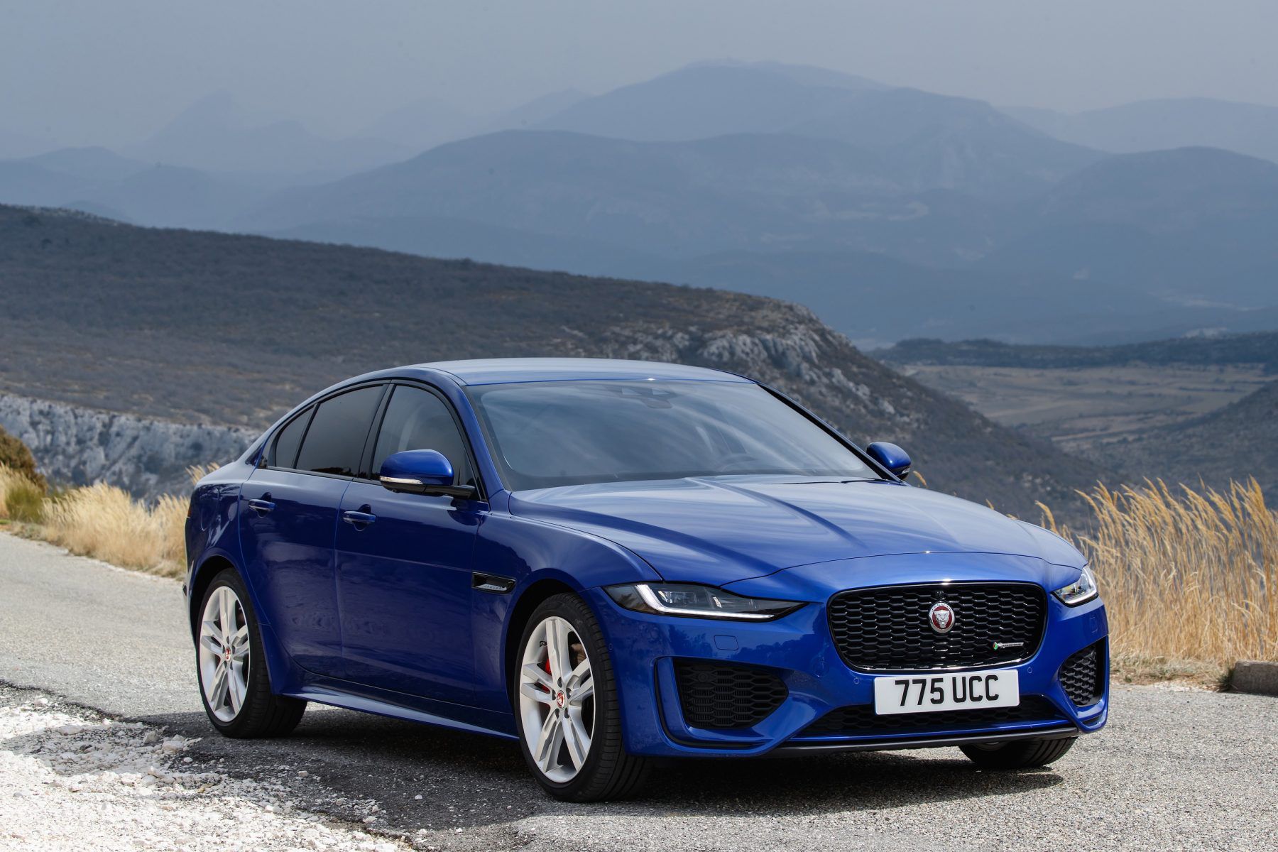 BlueJaguar XE parked with mountains in the background