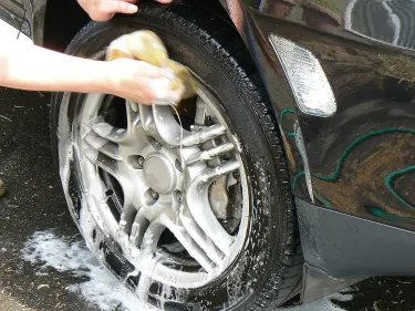 someone washing an alloy wheel with a sponge