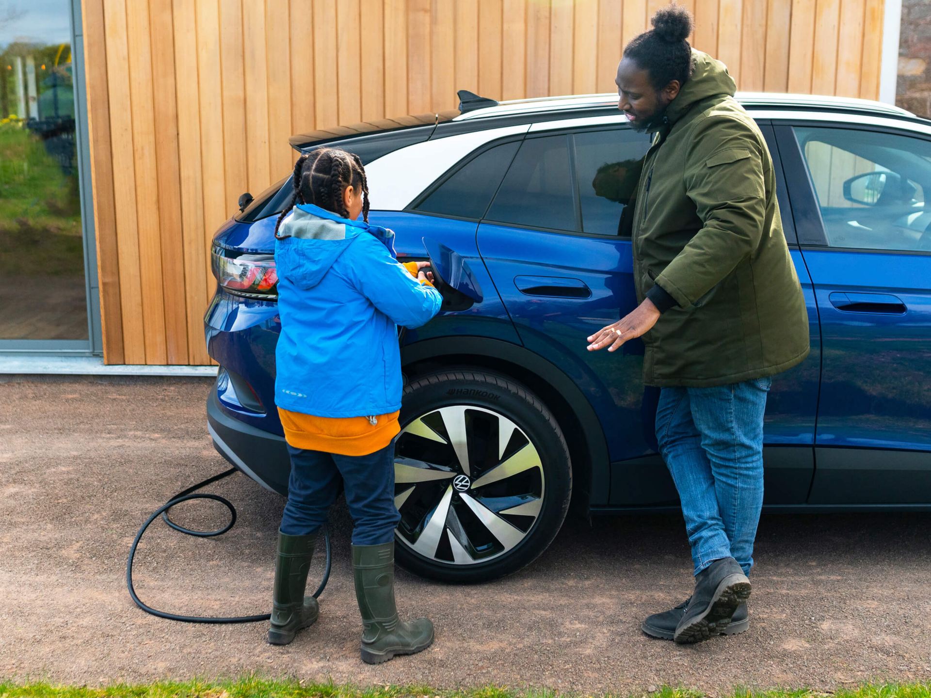 Blue Volkswagen ID.4 being plugged in by a child with an adult watching