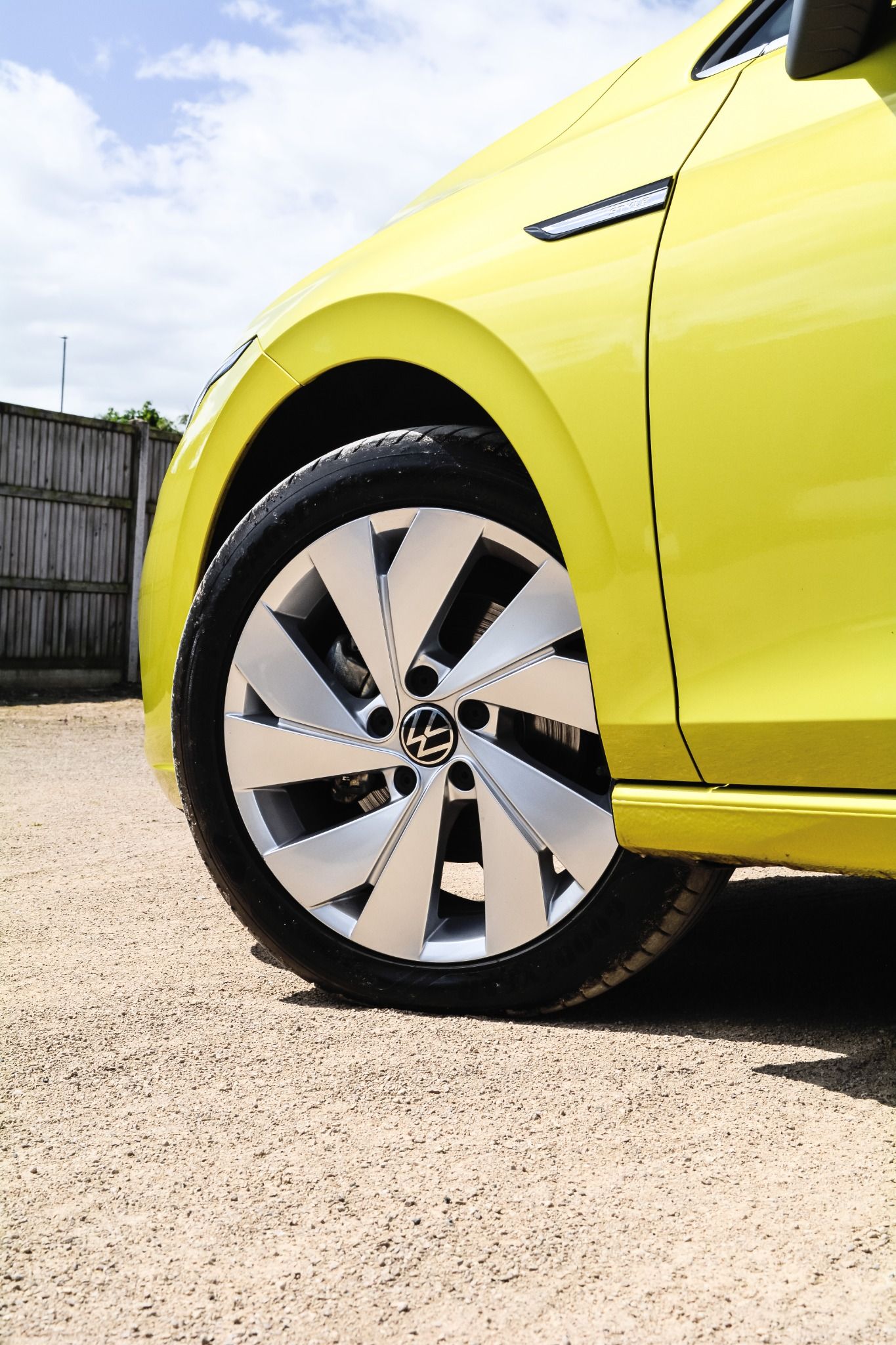 Close up image of silver alloy wheels on yellow Volkswagen Golf