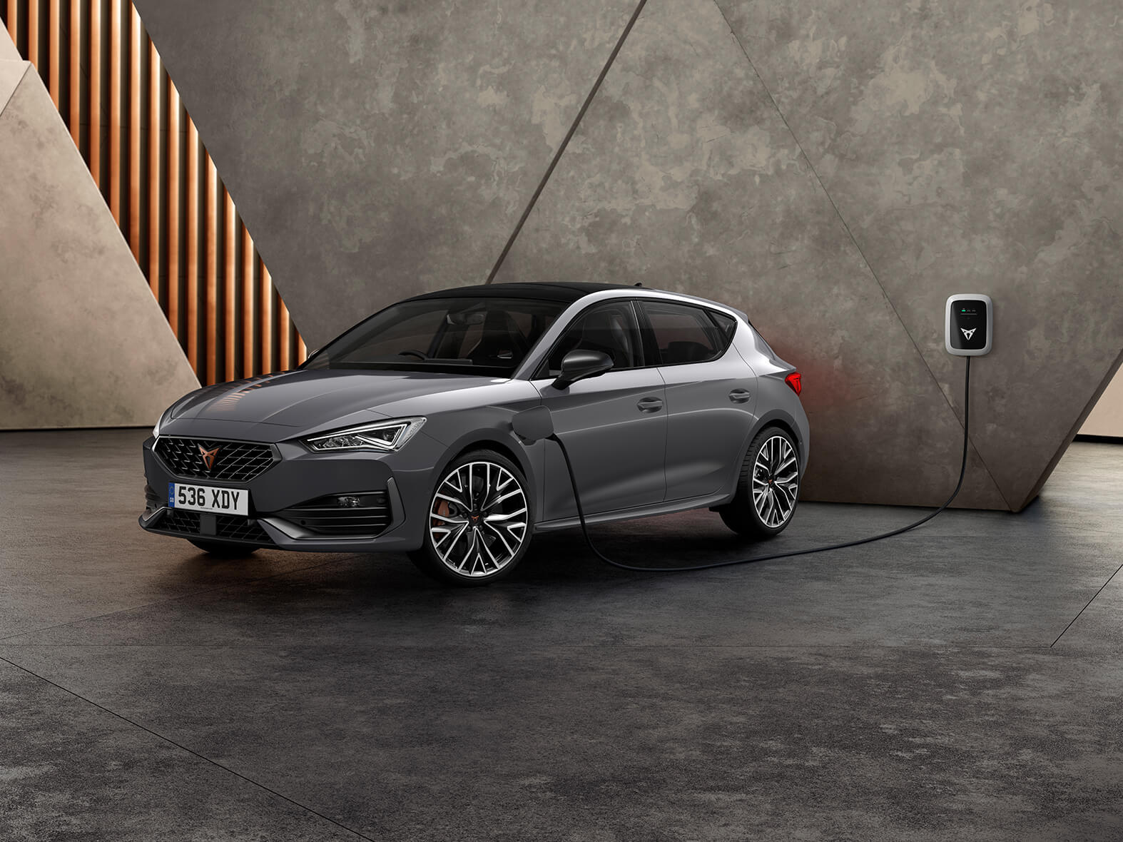 Cupra Leon e hybrid in grey plugged into wall charger