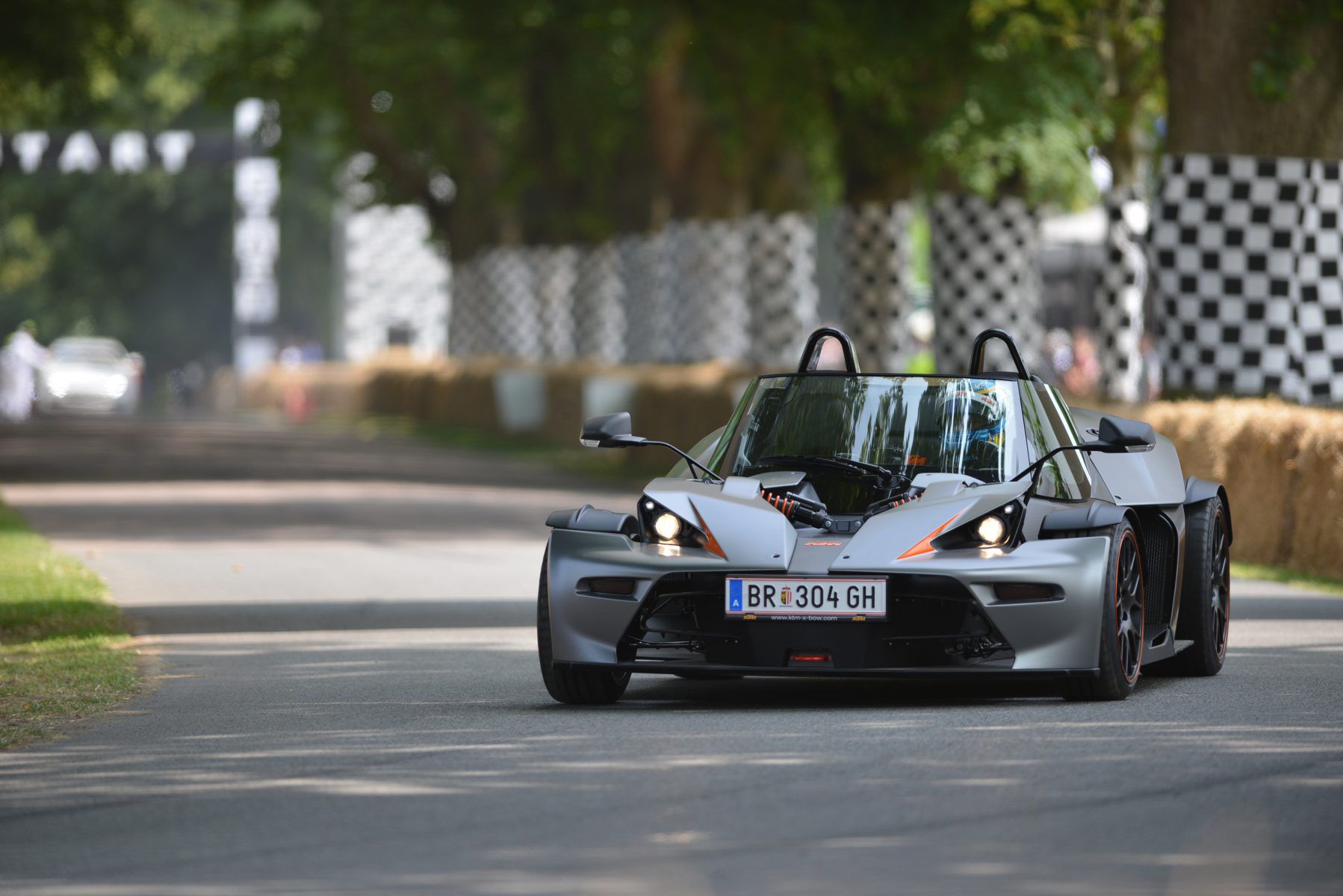 Front view of a grey KTM X-Bow driving on a track
