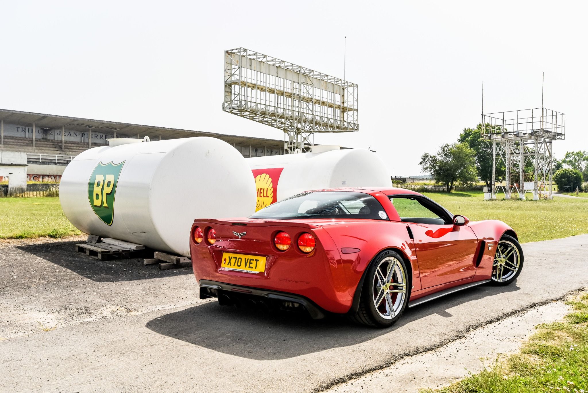 A red sports car next to fueling tanks at an old race track