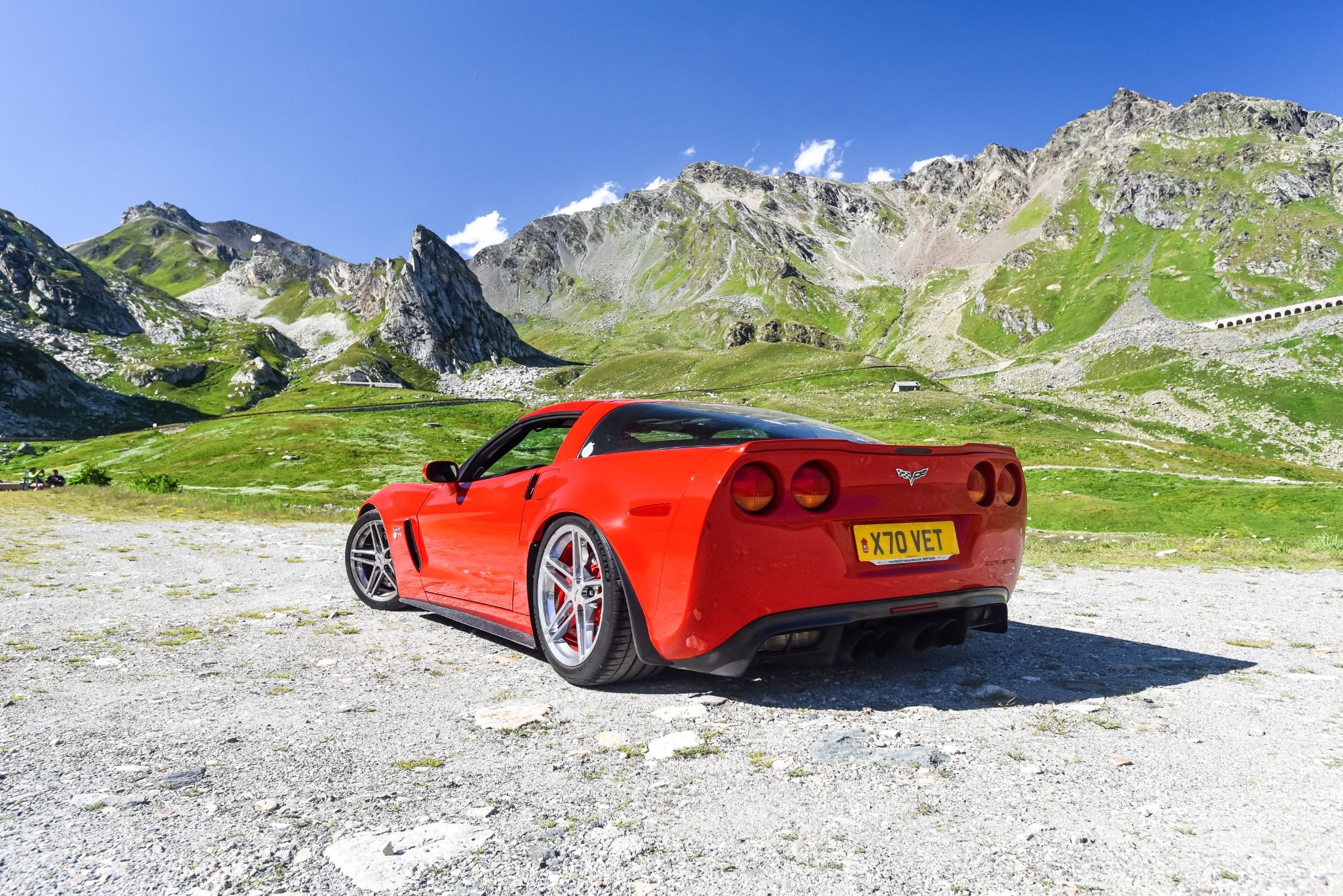 Rear of a red sports car in front of mountains