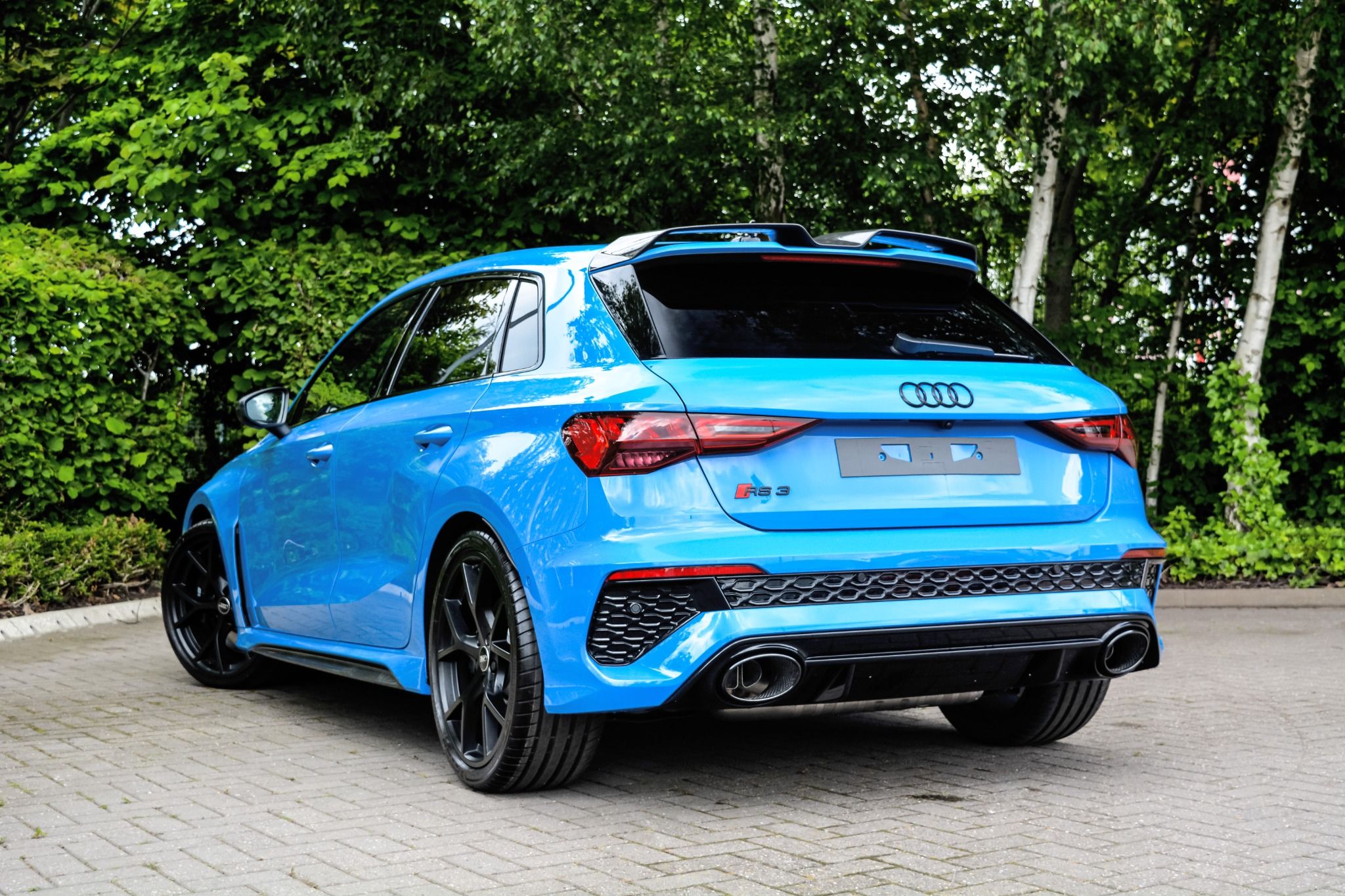 Rear of Blue Audi RS3 in front of trees