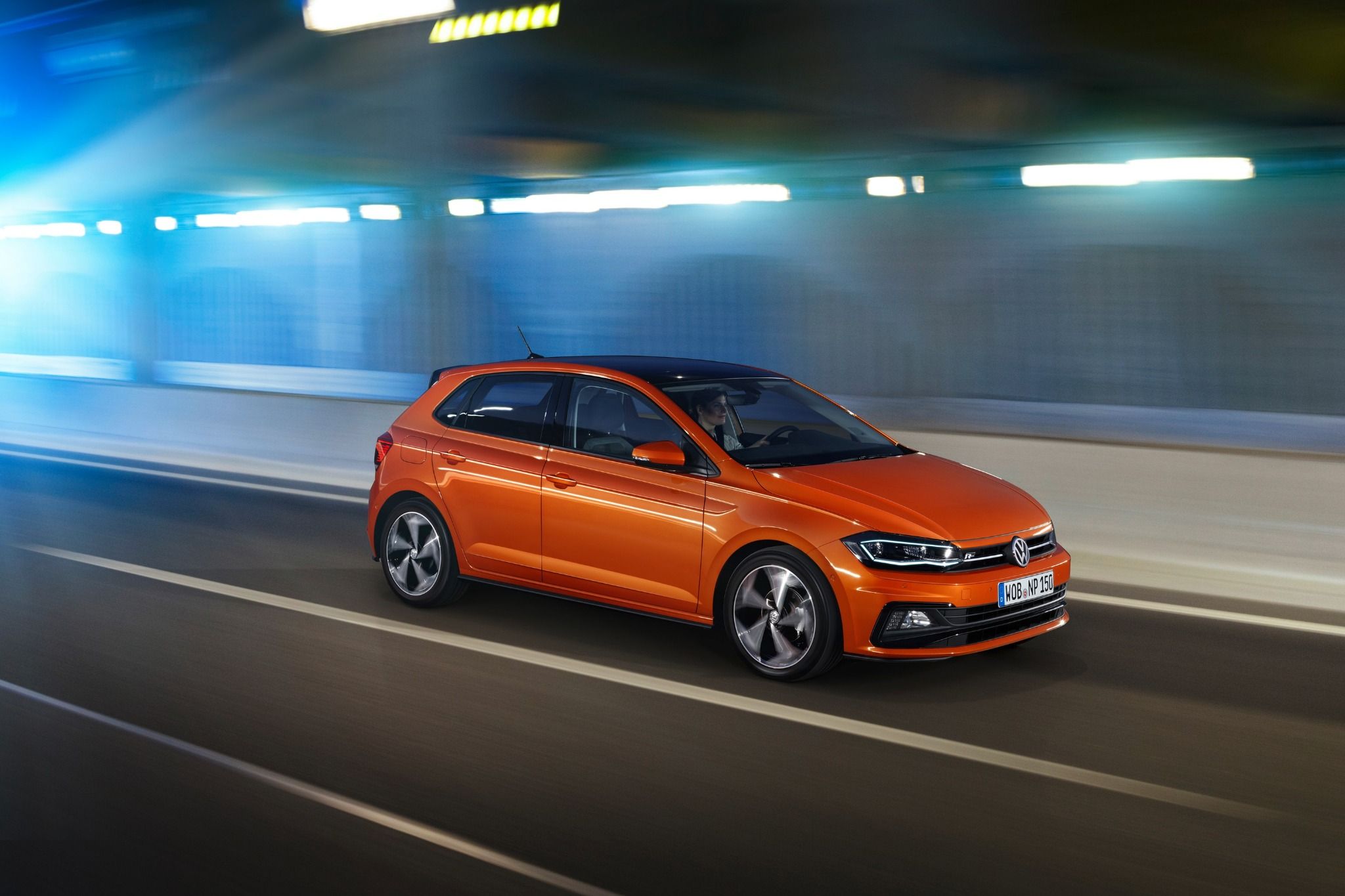 Front view of an orange VW Polo R driving down a road