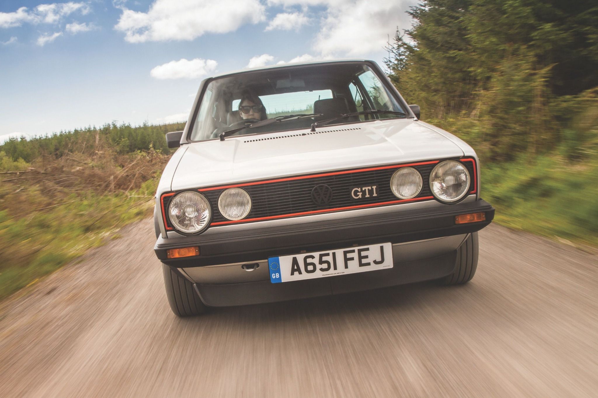Front view of an MK1 Volkswagen Golf GTI driving on a road