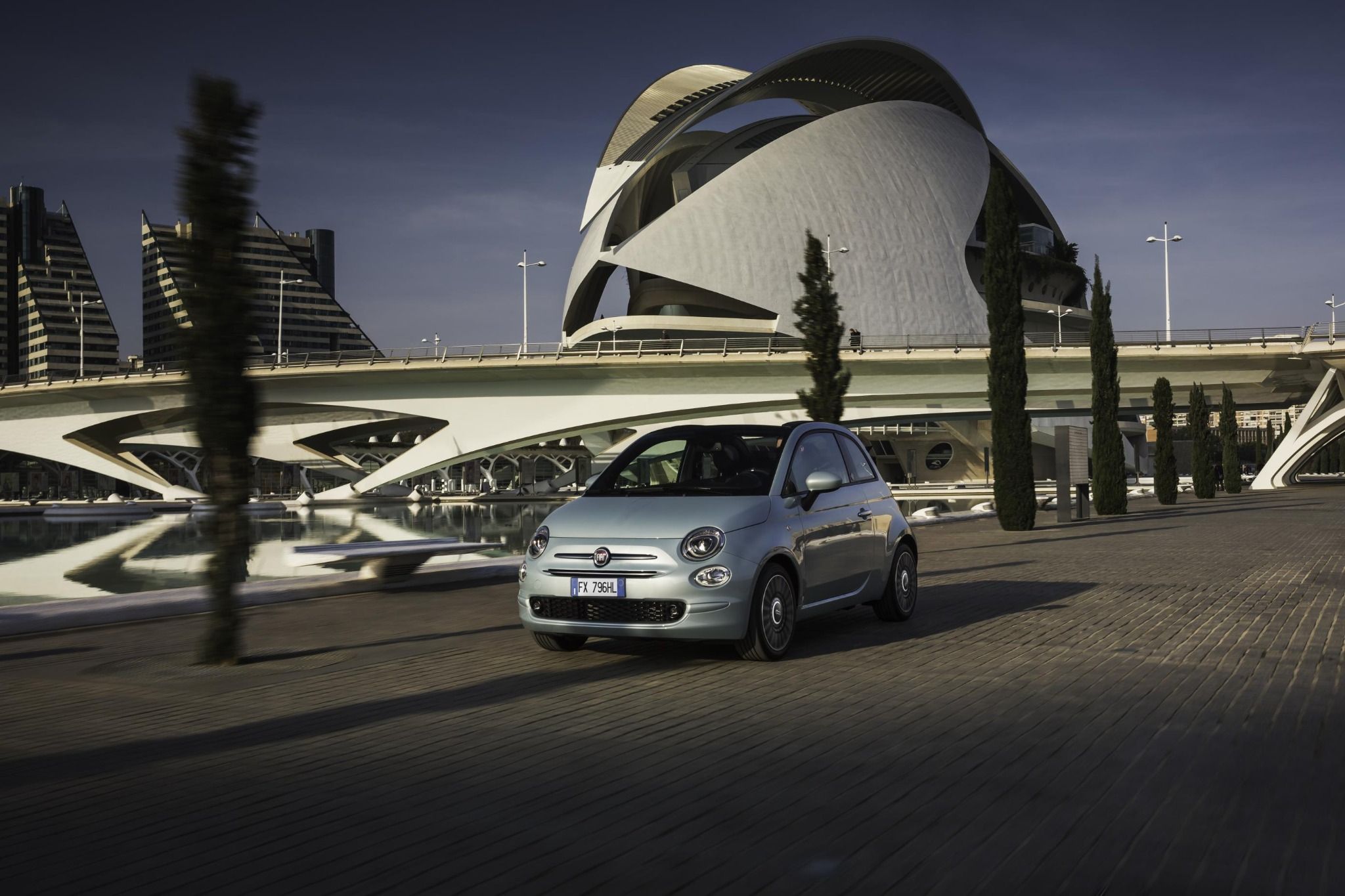 Silver Fiat 500 1.0 Mild Hybrid driving down a road next to water
