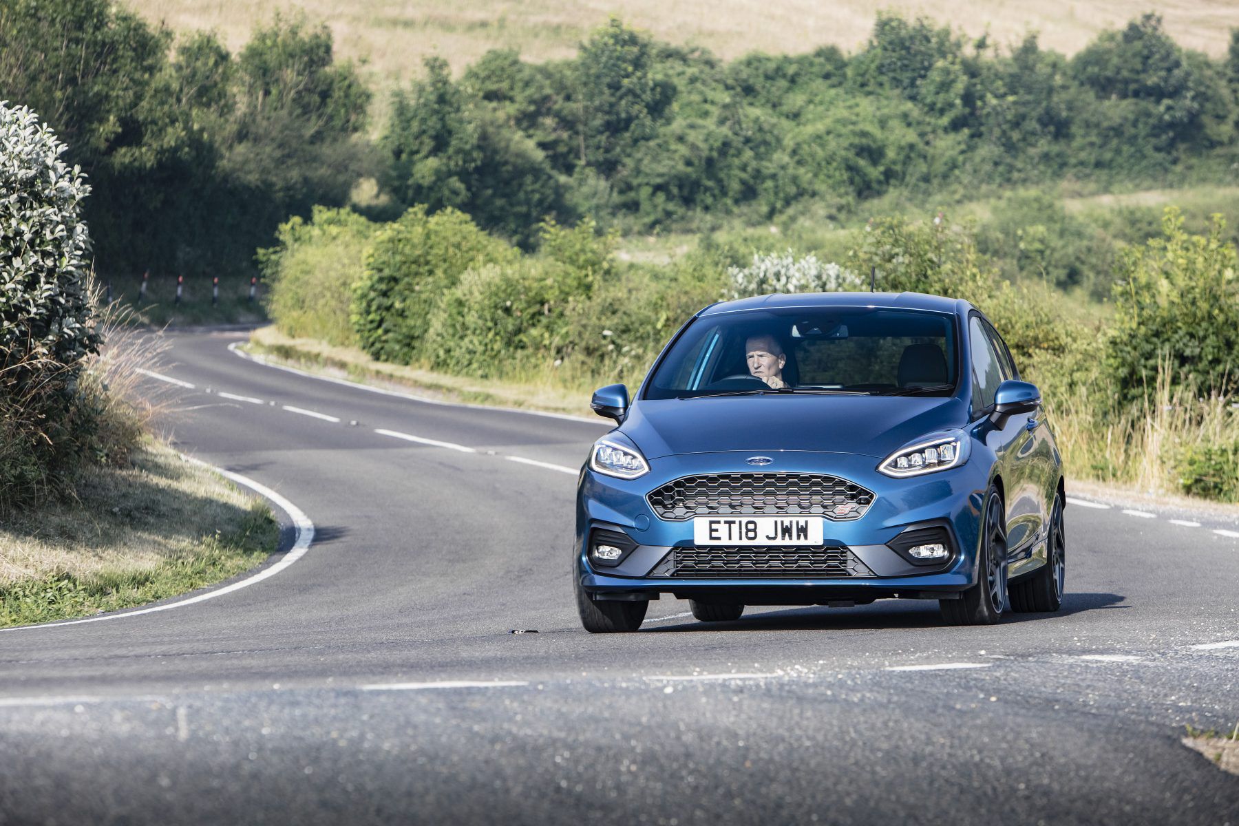 Front view of a blue Ford Fiesta ST driving down a road