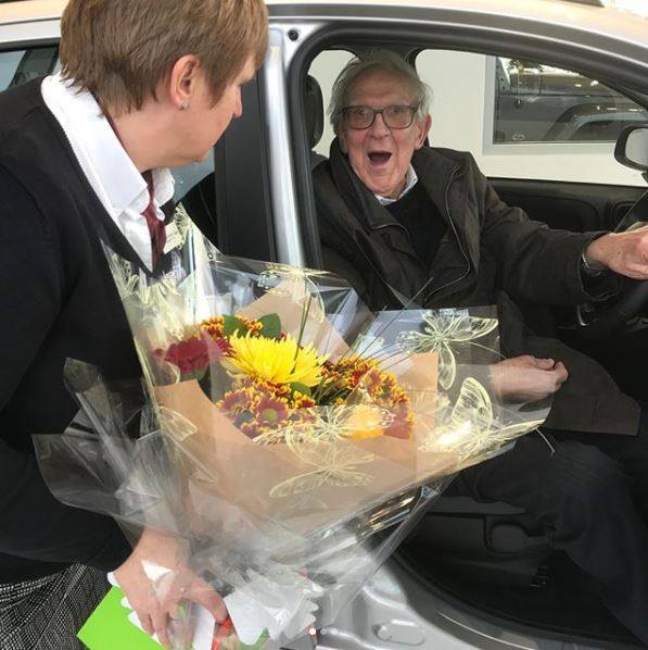 A man getting flowers at a car handover