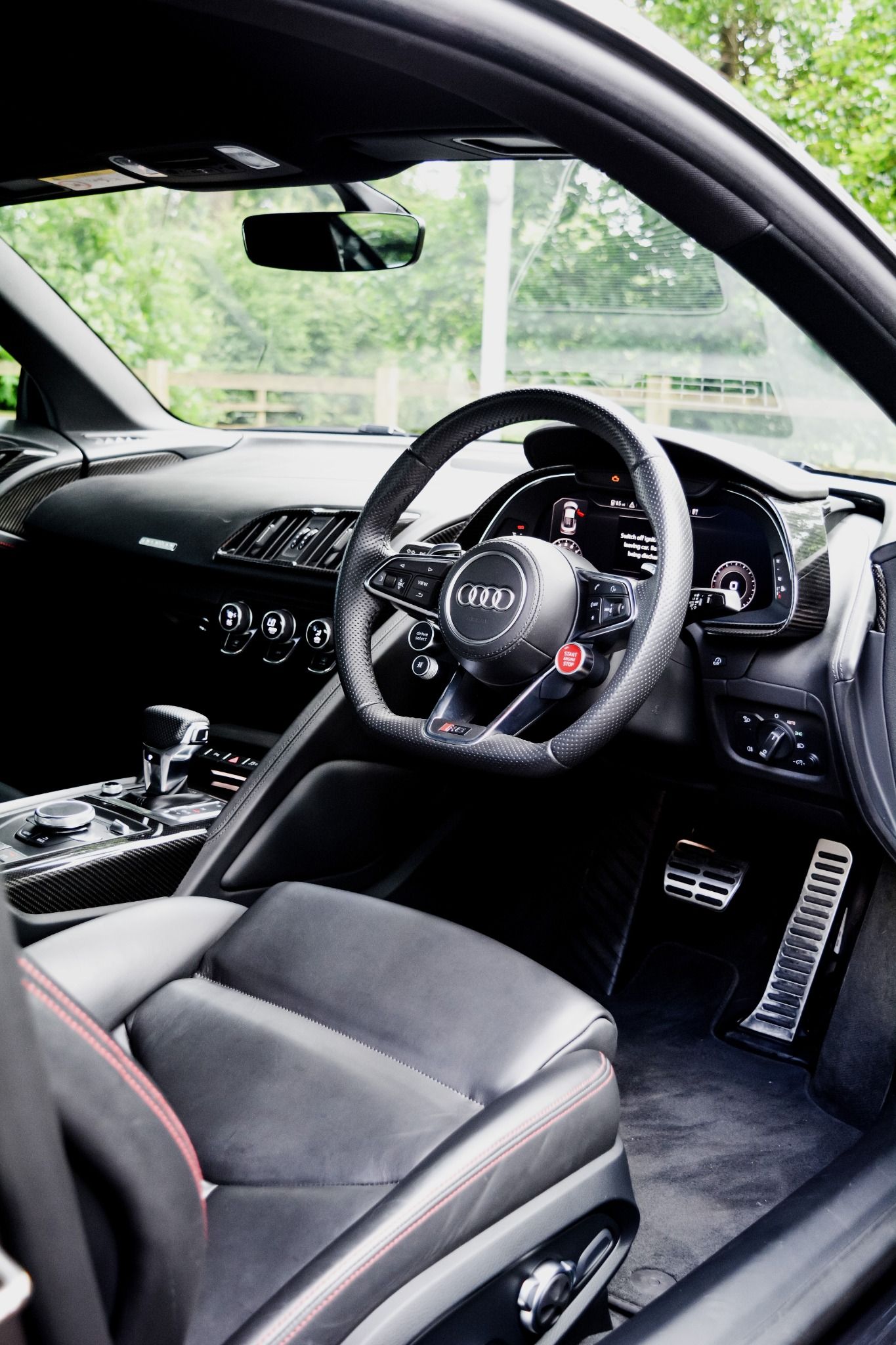 Interior of Audi R8 coupe showing leather seats, flat bottom steering wheel and stop start button