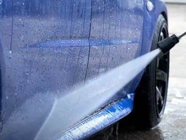 Jet washer spraying water at a car
