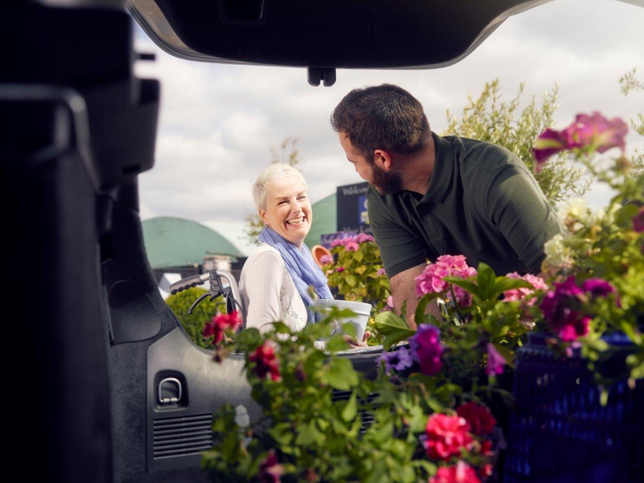 Man helping lady put plants in the back of her car