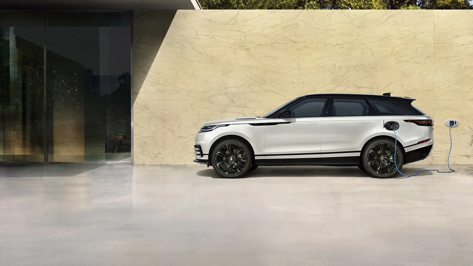 Side view of a white Range Rover Evoque plugged into a charger