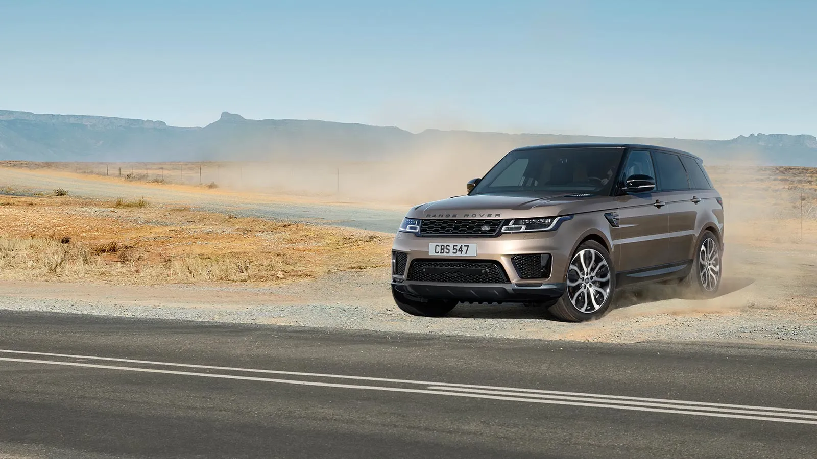 Range Rover driving across dusty dirt road
