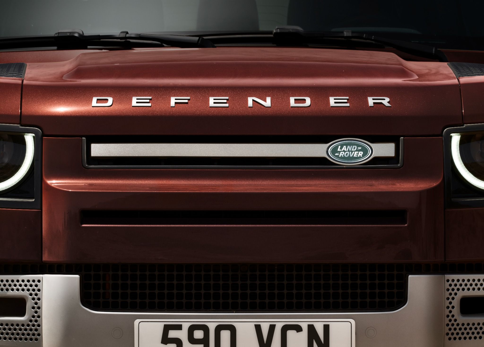 Close up of land rover defender 130 front grille in sedona red.