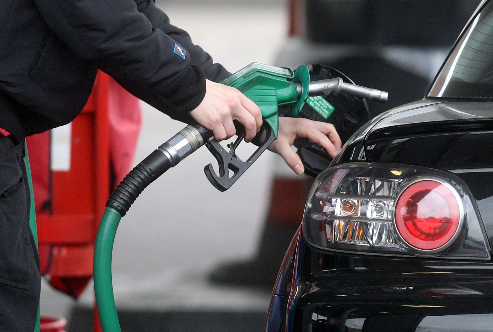 man fueling up his black car at the petrol station