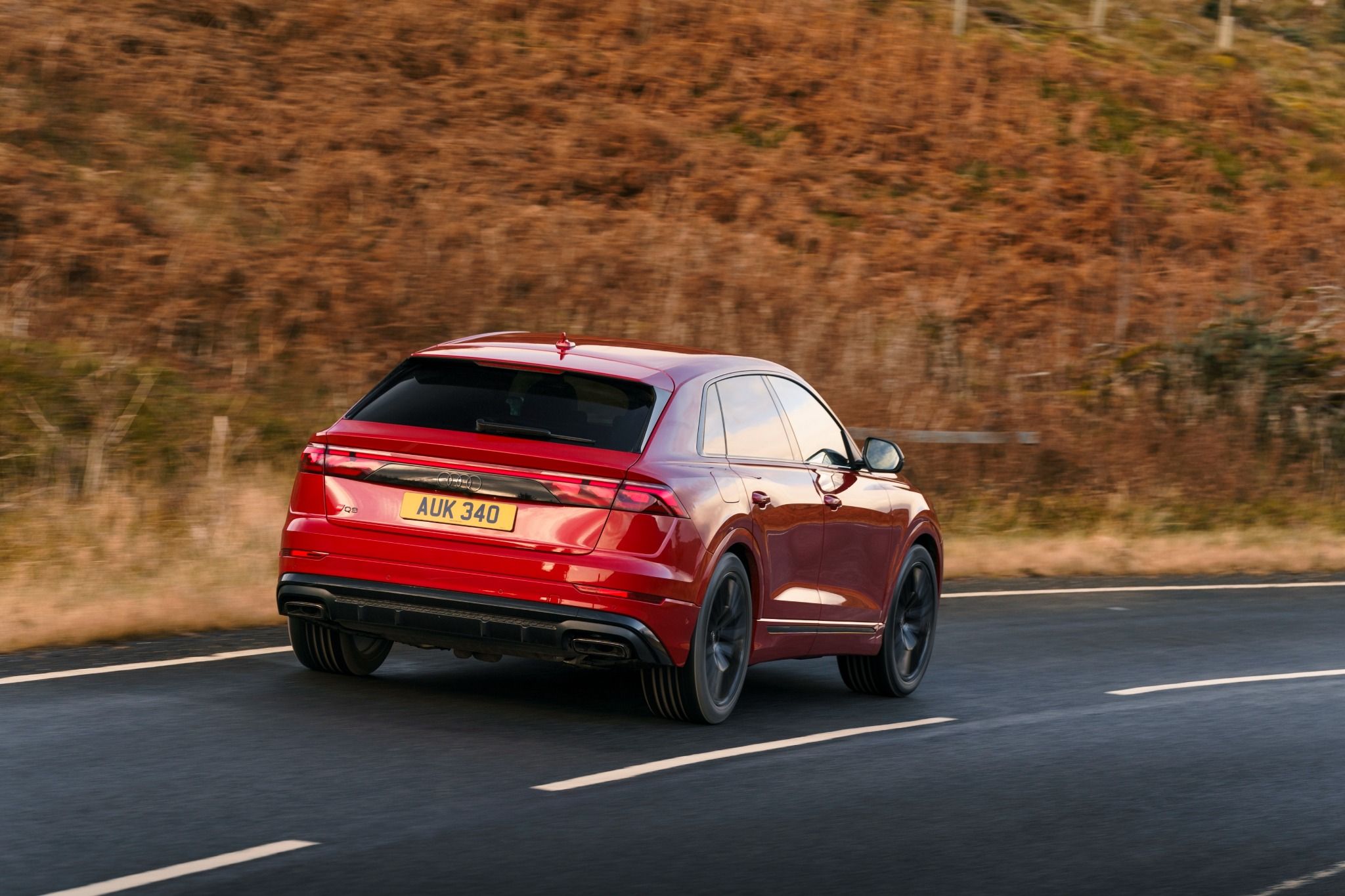 Red Audi Q8 SUV driving past trees