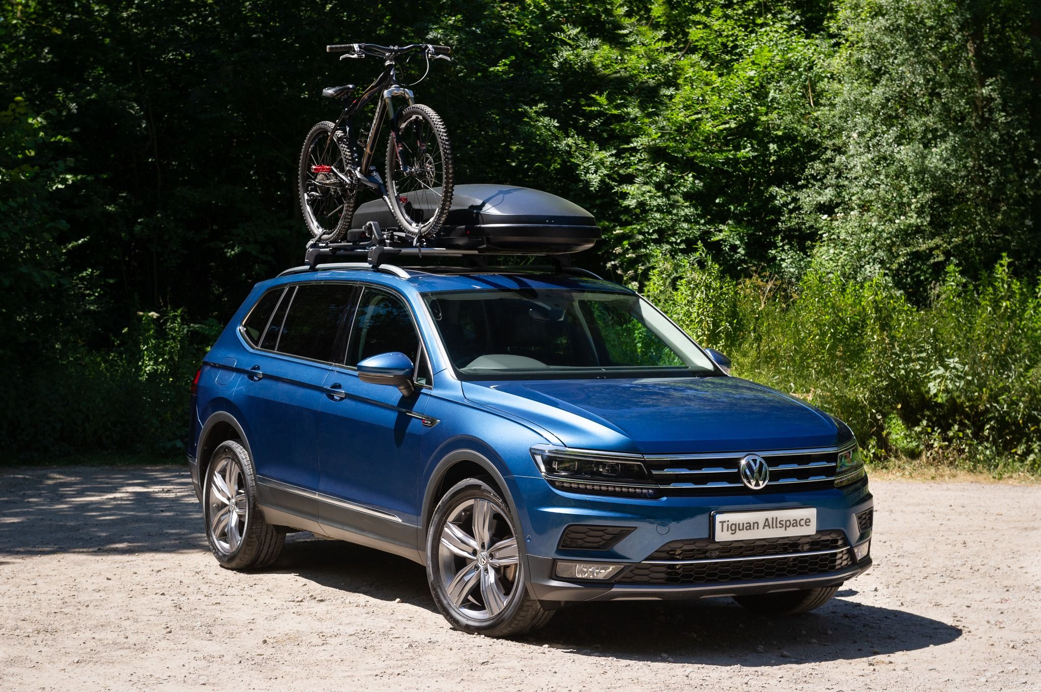 Blue Tiguan Allspace with a roof box and a bike on the roof rails