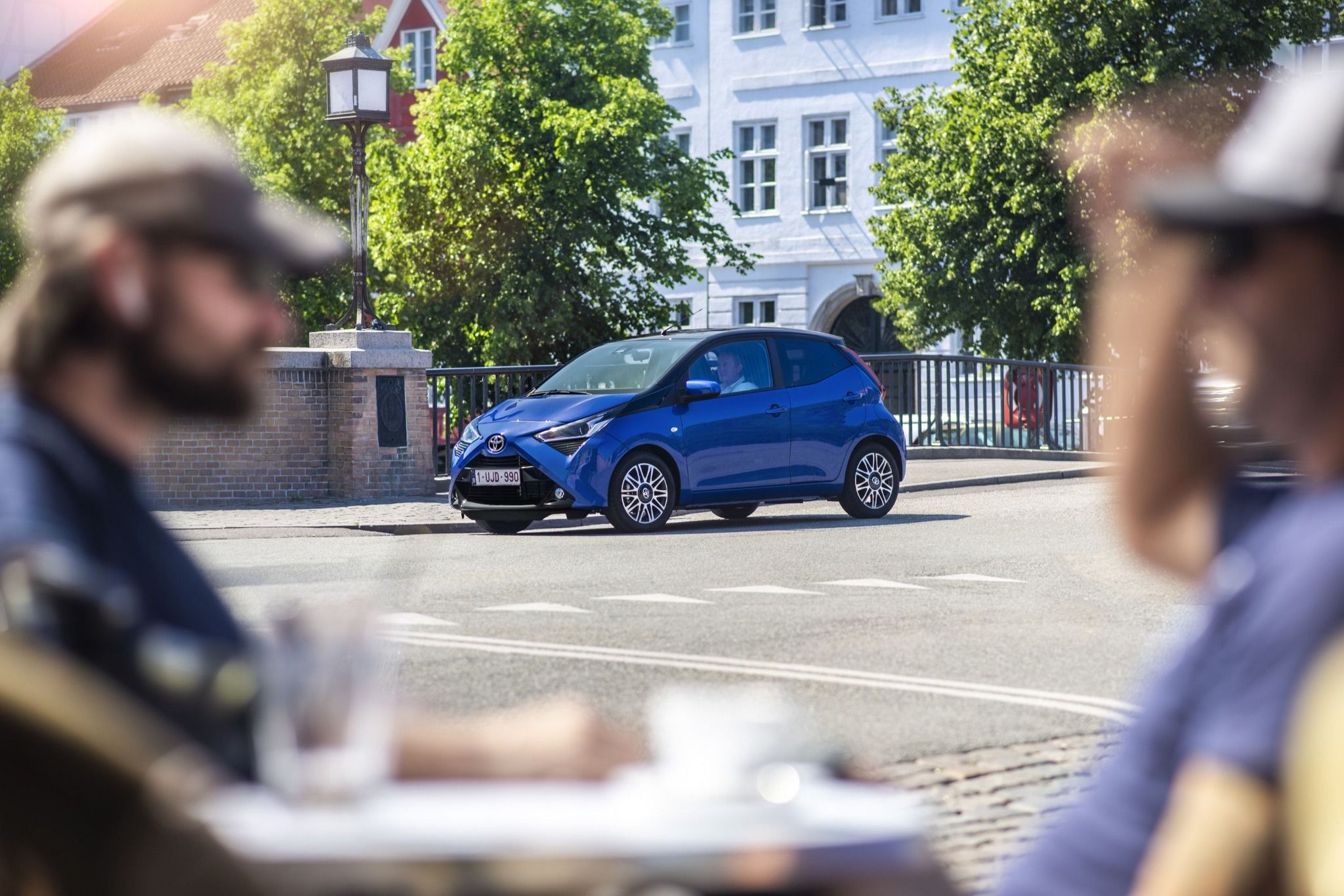 people sitting at a table talking with a blue car in centre shot