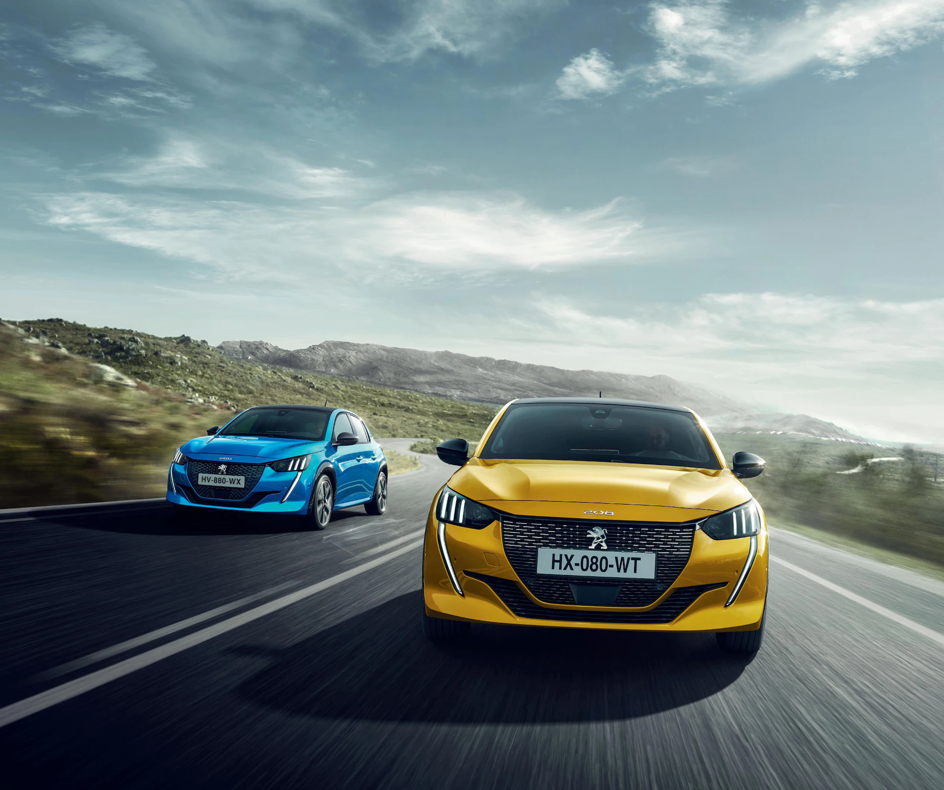 Peugeot 208 in blue and yellow driving down a road