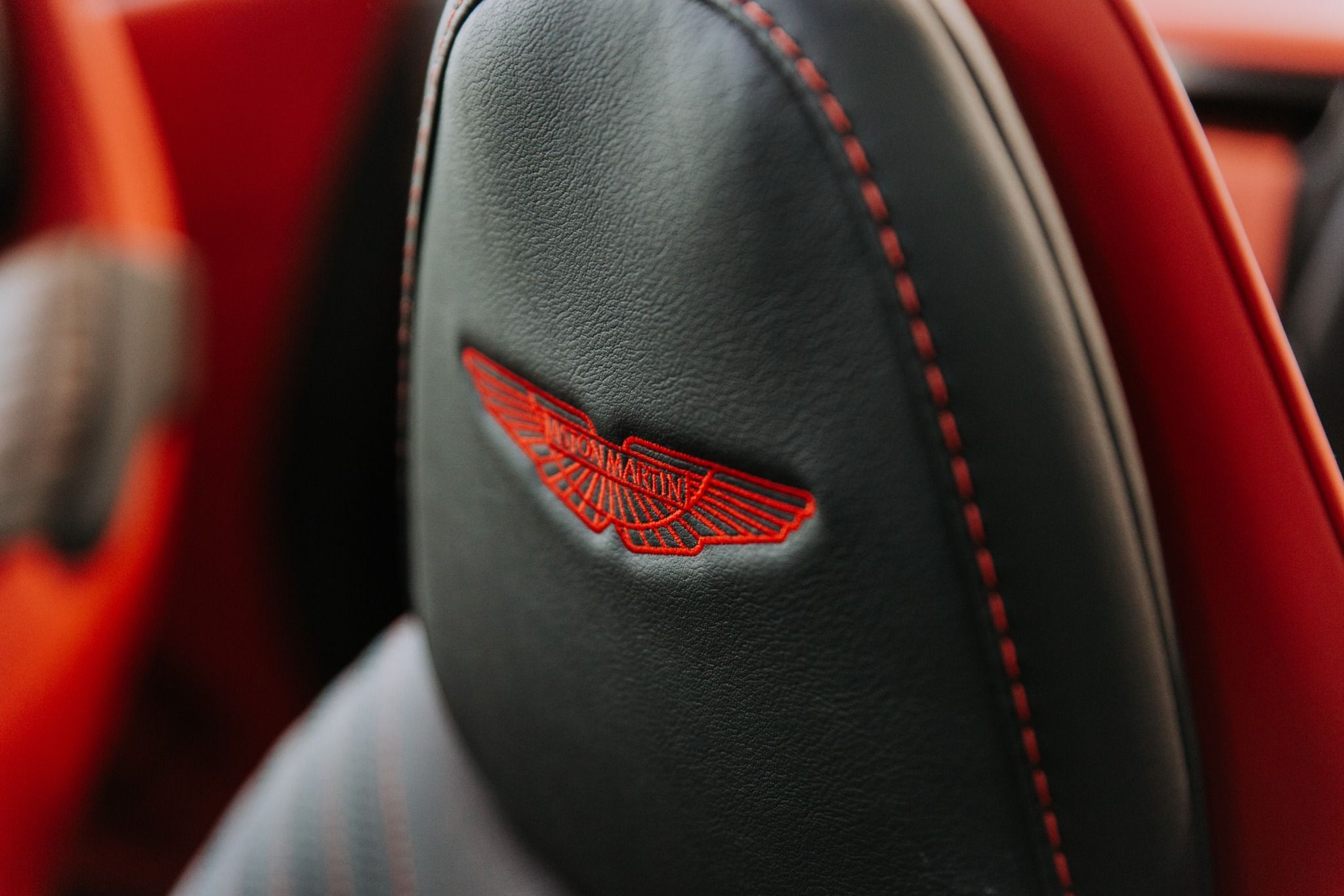 Close up of leather seats with red embroidery from an Aston Martin