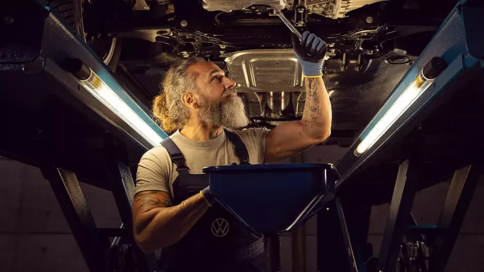 Volkswagen Commercial Vehicle technician underneath a van with a spanner