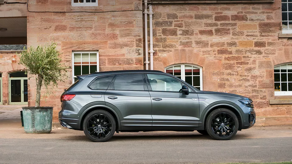 Grey Volkswagen Touareg side parked next to house