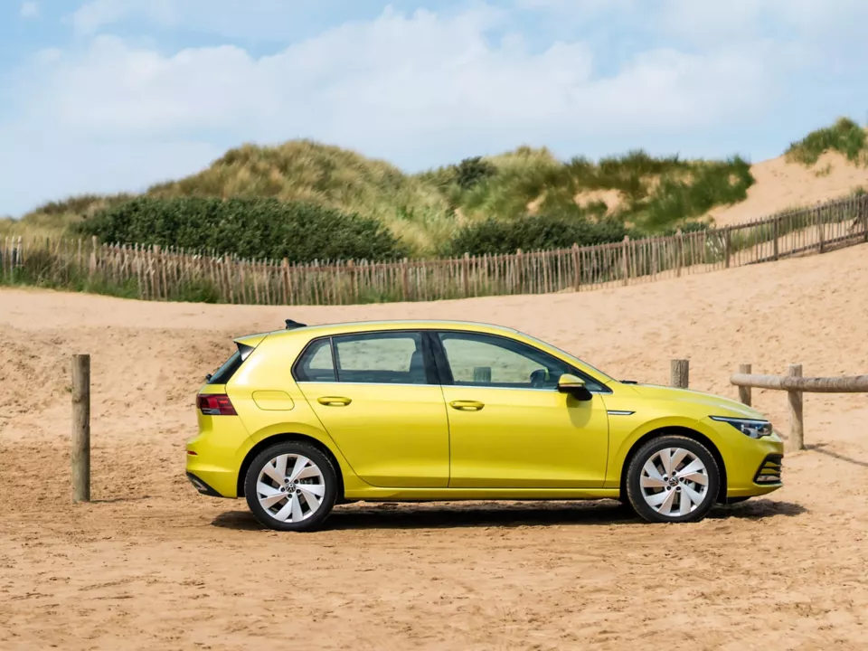 side view of yellow golf parked on a beach
