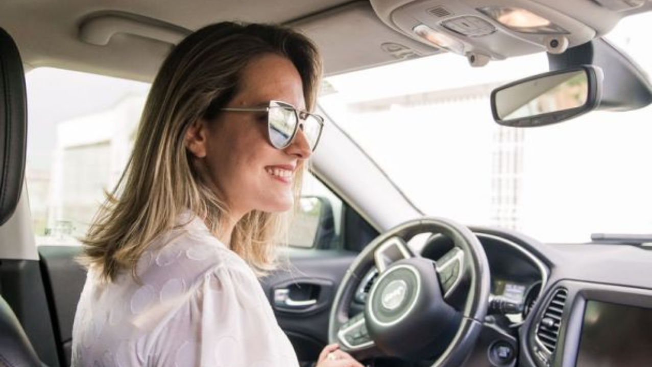 Woman smiling whilst driving car
