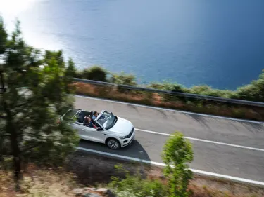 White Volkswagen T-Roc cabriolet driving down a road