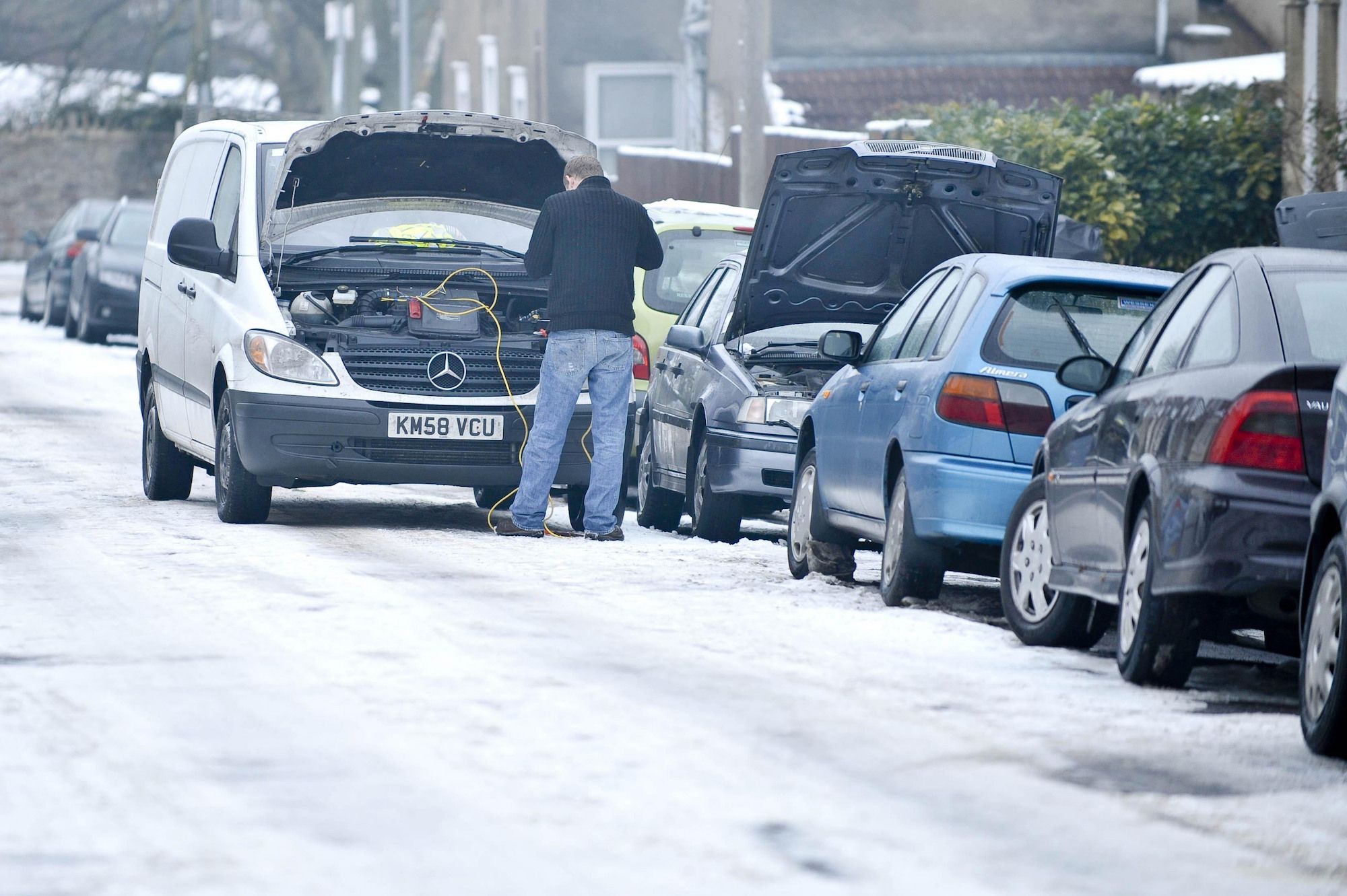 Man checking his car battery in the snow