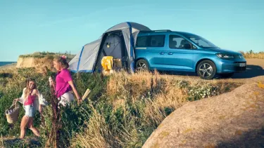 Blue Volkswagen Caddy California parked by the beach