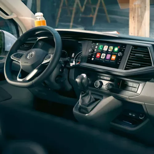 interior view of volkswagen transporter panel van  showing black leather steering wheel, gear stick and media system