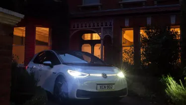 Volkswagen ID3 parked on driveway with headlights illuminated