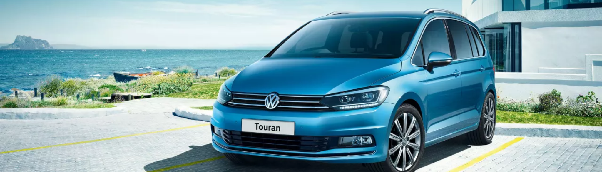Blue Volkswagen Touran parked by waterfront